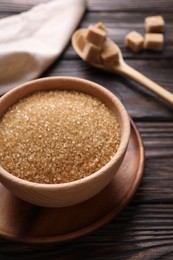 Bowl and spoon with brown sugar on wooden table