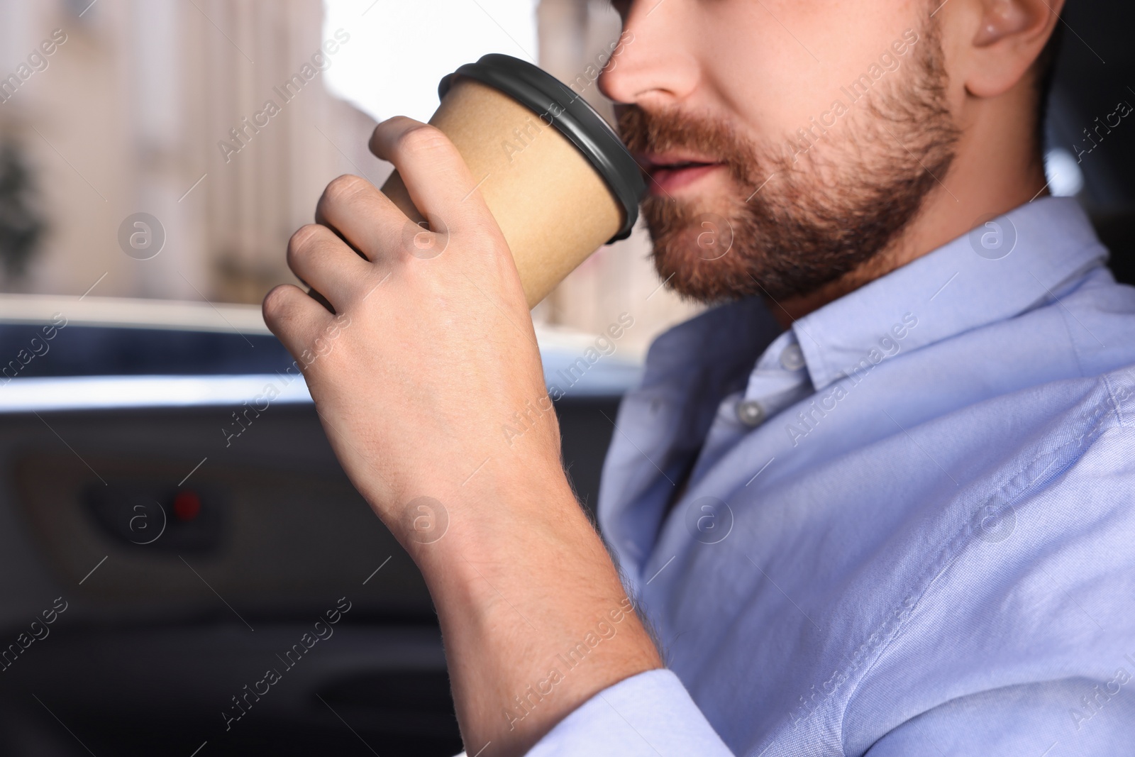 Photo of To-go drink. Man drinking coffee in car, closeup