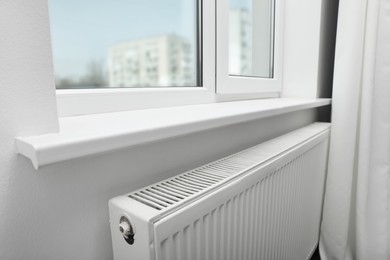 Photo of Modern radiator under window at home. Central heating system