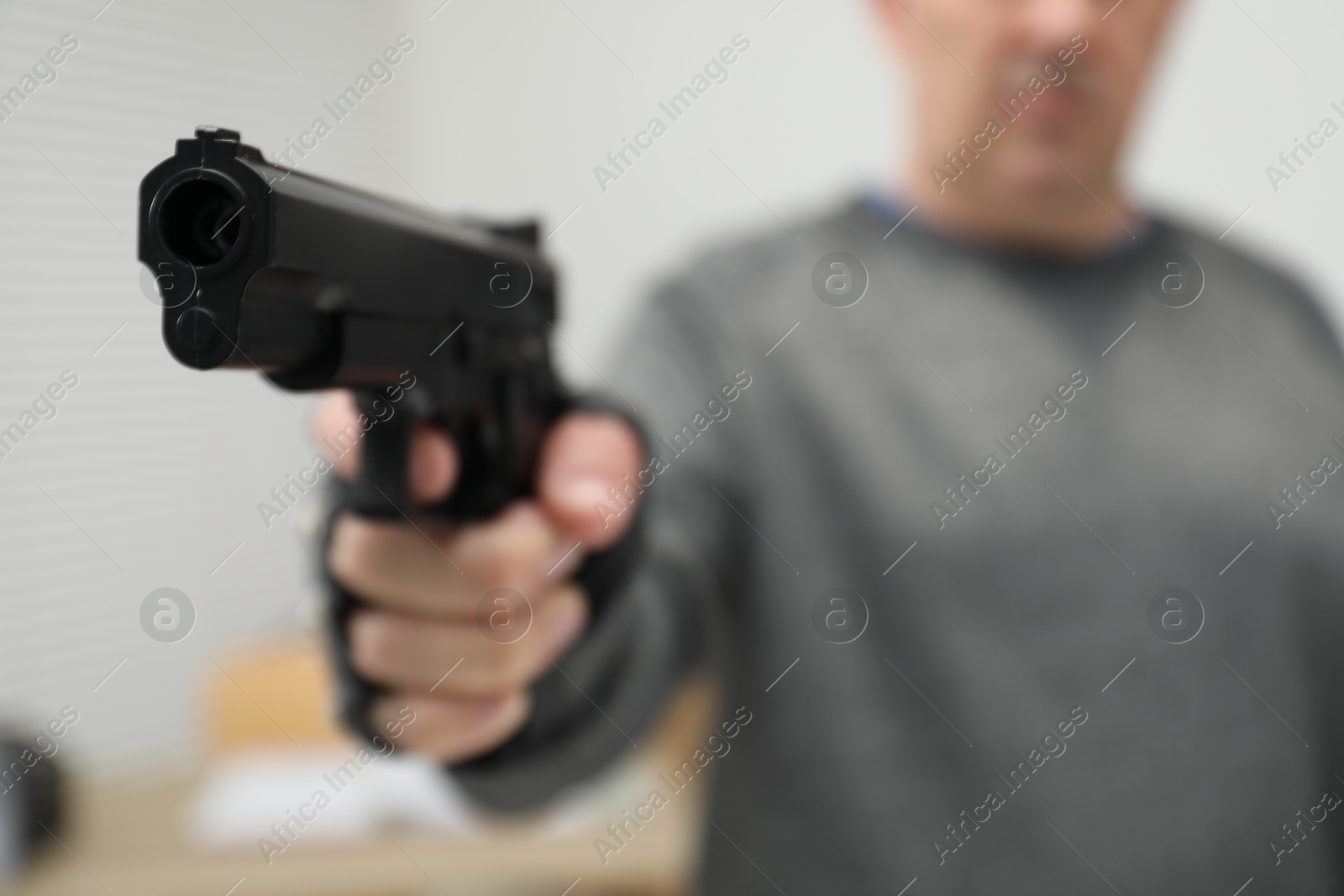 Photo of Dangerous criminal with gun indoors, selective focus. Armed robbery