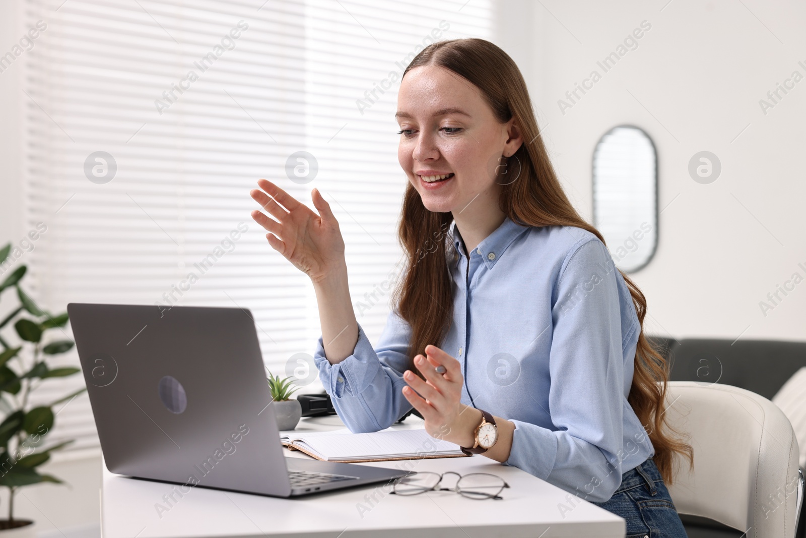 Photo of E-learning. Young woman using laptop during online lesson at white table indoors