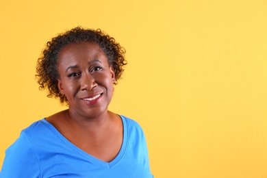 Portrait of happy African-American woman on yellow background