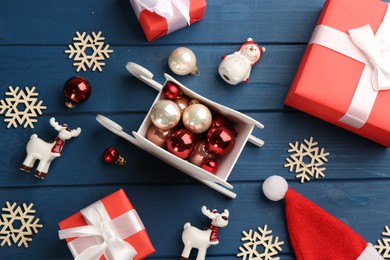 Beautiful Christmas composition with miniature sleigh on blue wooden table, flat lay