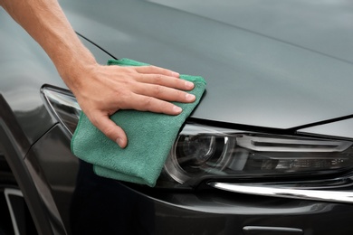 Photo of Man washing car headlight with rag, closeup