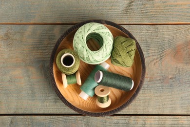 Color sewing threads in bowl on light blue wooden table, top view