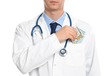 Doctor putting bribe into pocket on white background, closeup. Corruption in medicine