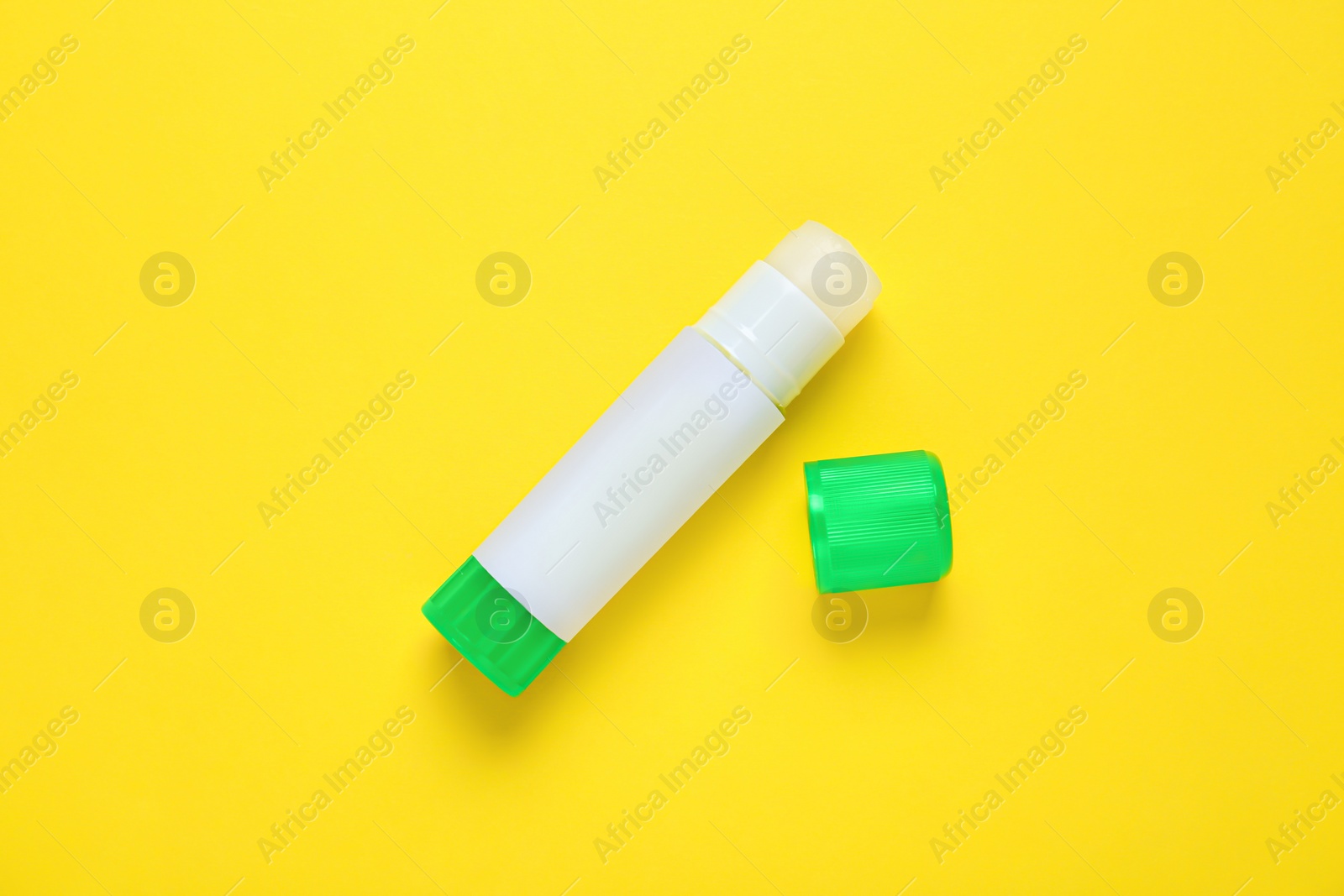 Photo of Blank glue stick on yellow background, top view