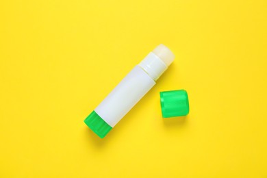 Photo of Blank glue stick on yellow background, top view