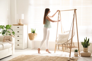 Photo of Woman near comfortable hammock chair at home