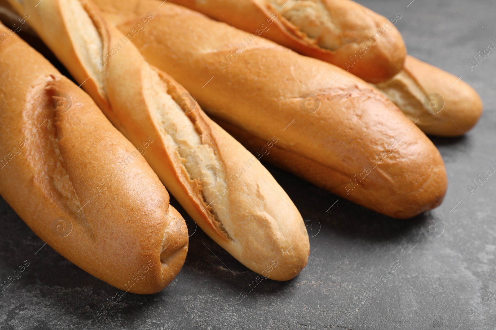 Photo of Different tasty baguettes on grey table, closeup