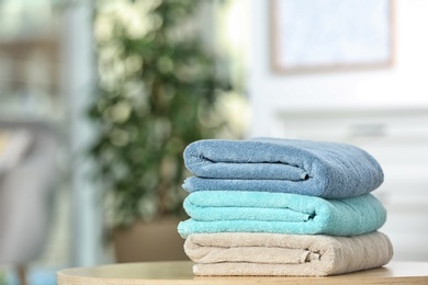 Stack of folded clean soft towels on table indoors. Space for text