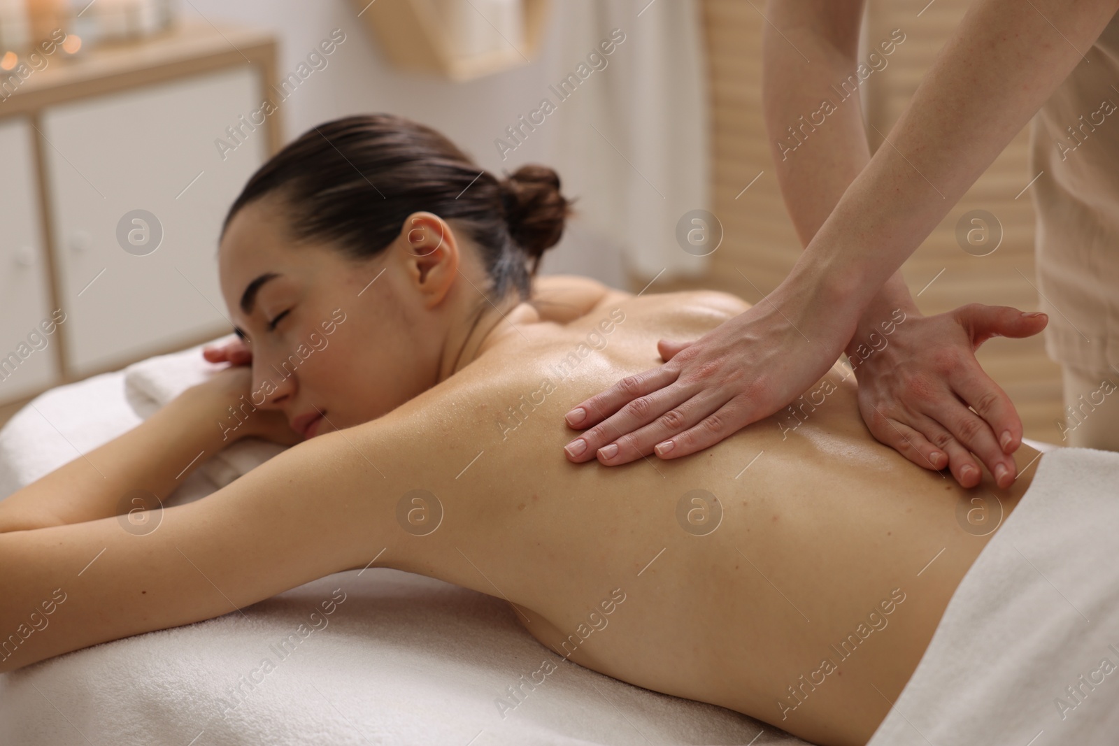 Photo of Woman receiving back massage on couch in spa salon