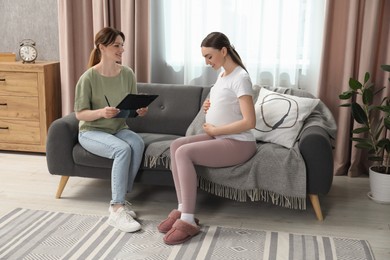 Doula working with pregnant woman on sofa at home. Preparation for child birth