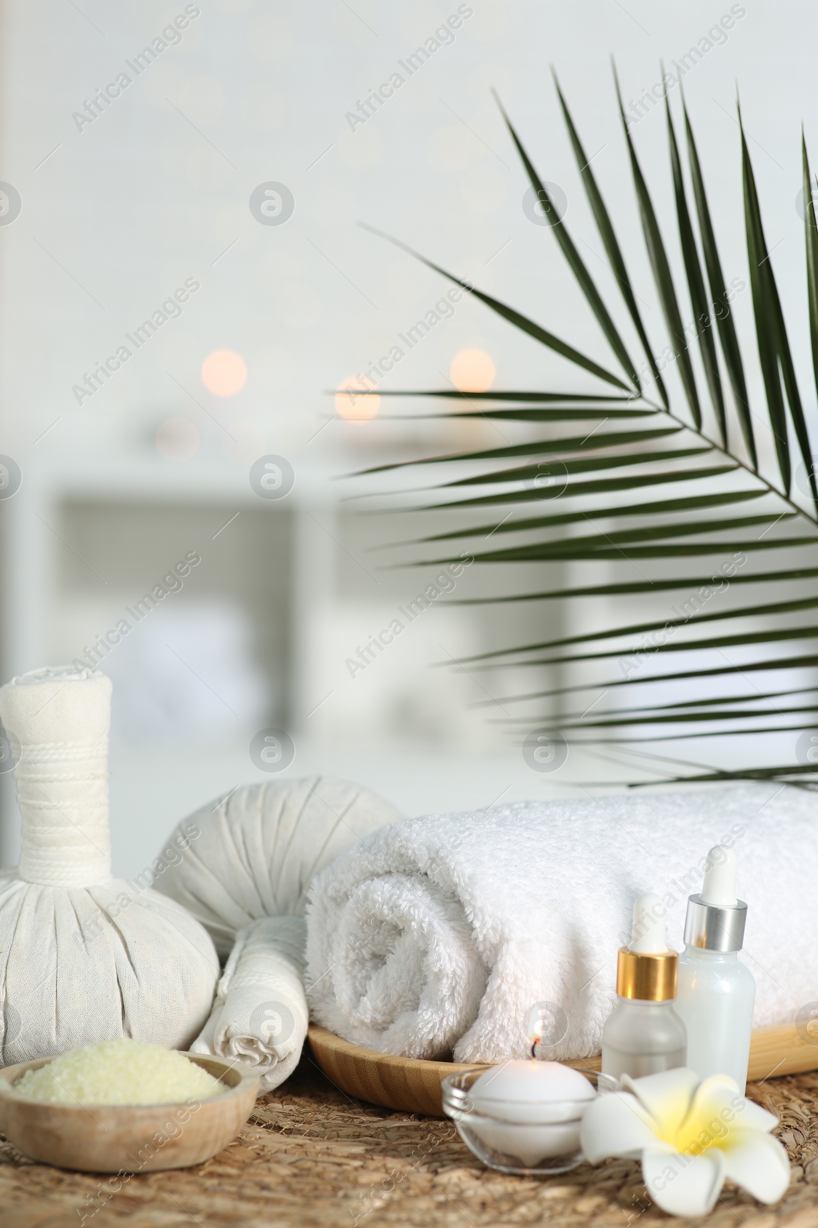 Photo of Composition with different spa products and plumeria flower on wicker mat indoors