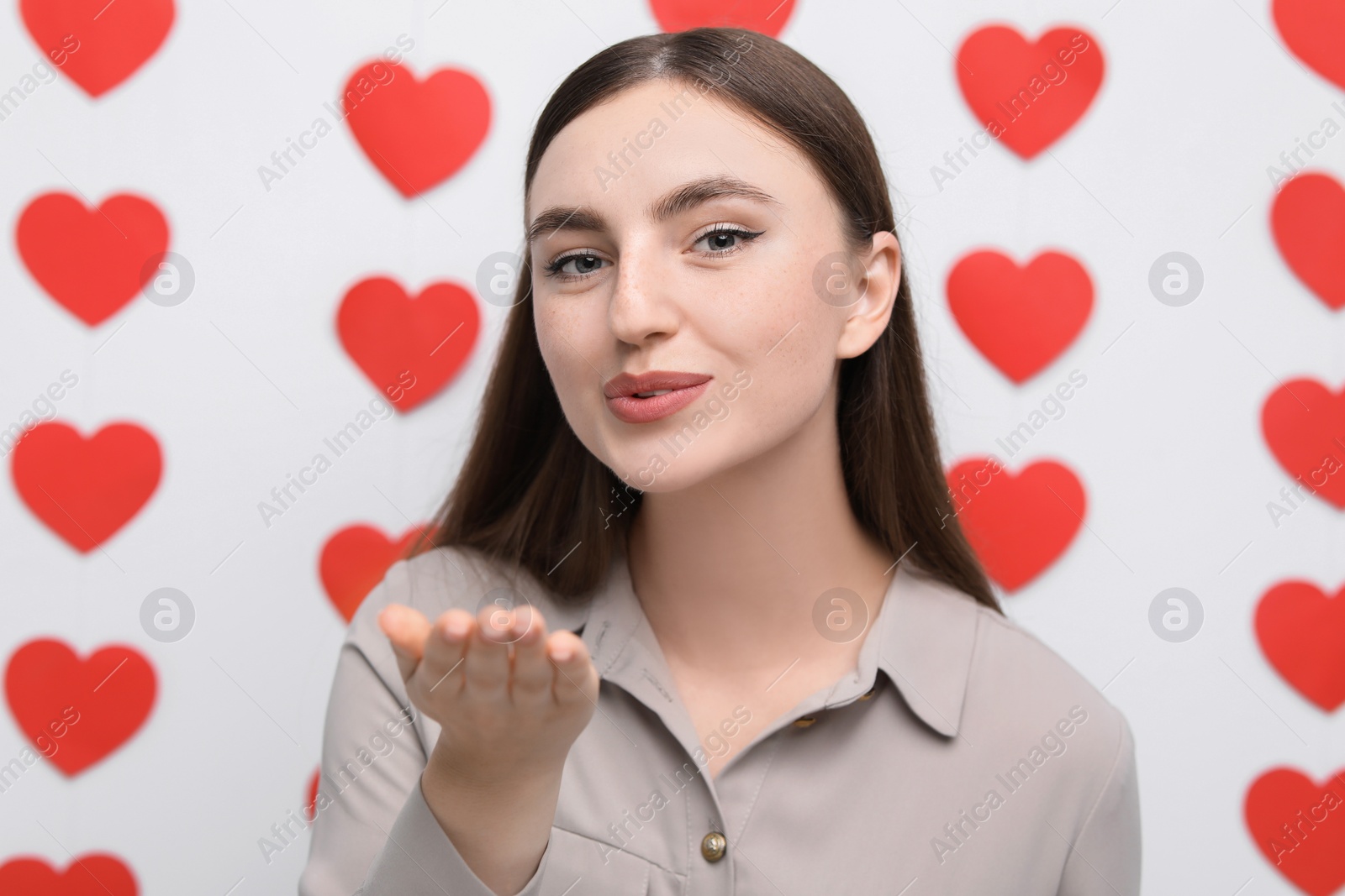 Photo of Beautiful woman blowing kiss on decorated background