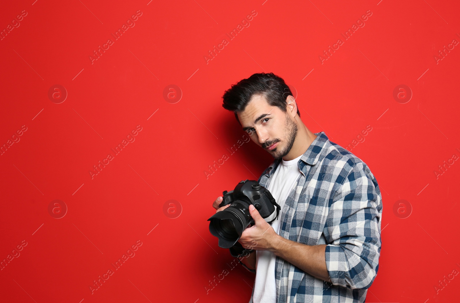 Photo of Young photographer with professional camera on red background. Space for text