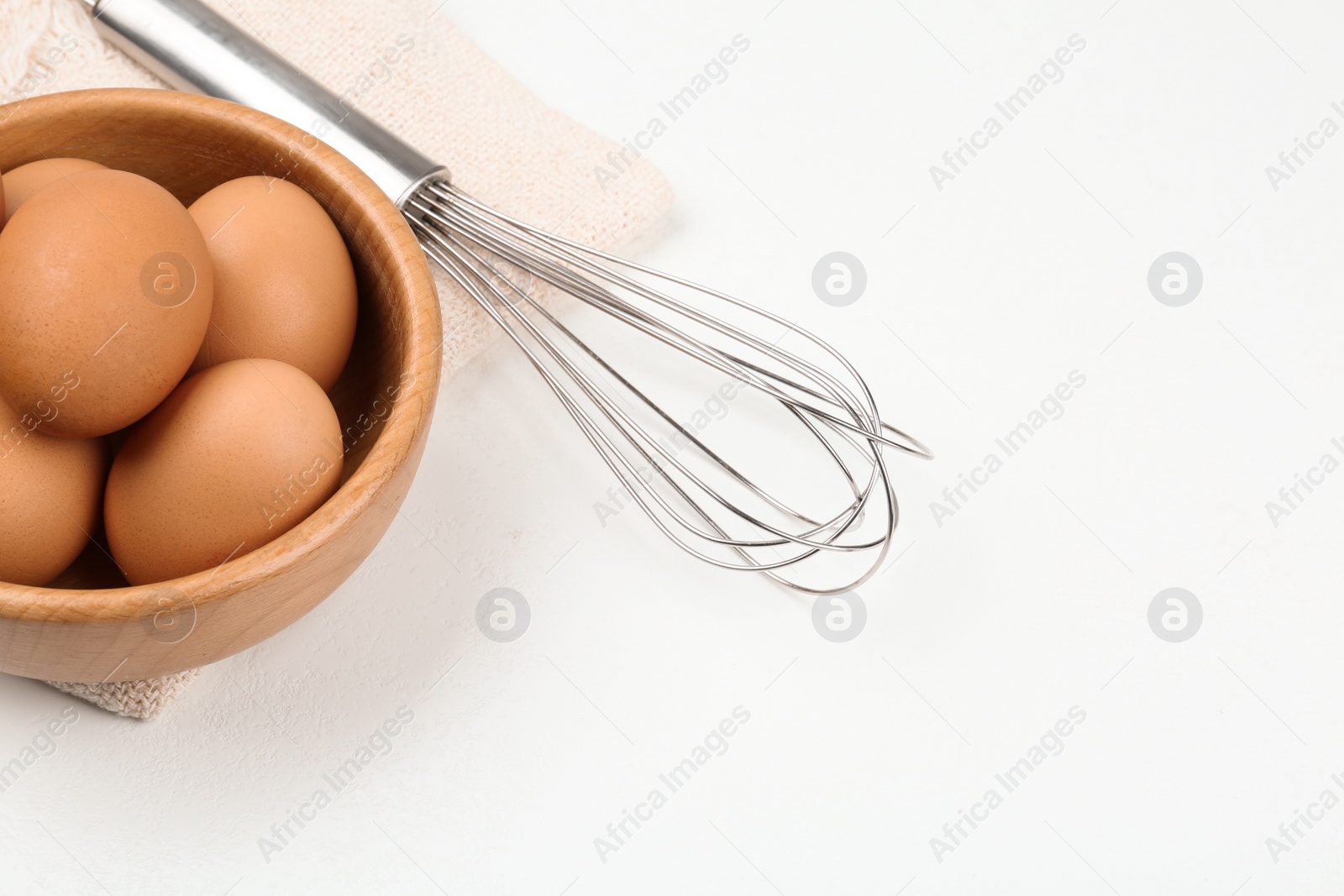 Photo of Raw eggs and whisk on white table. Baking pie