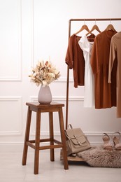 Photo of Stylish clothes hanging on rack in dressing room. Interior design