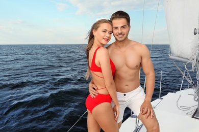 Photo of Young man and his beautiful girlfriend in bikini on yacht. Happy couple on vacation