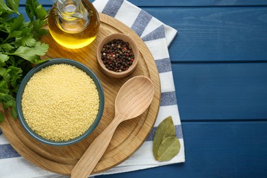 Photo of Bowl of raw couscous and ingredients on blue wooden table, flat lay. Space for text