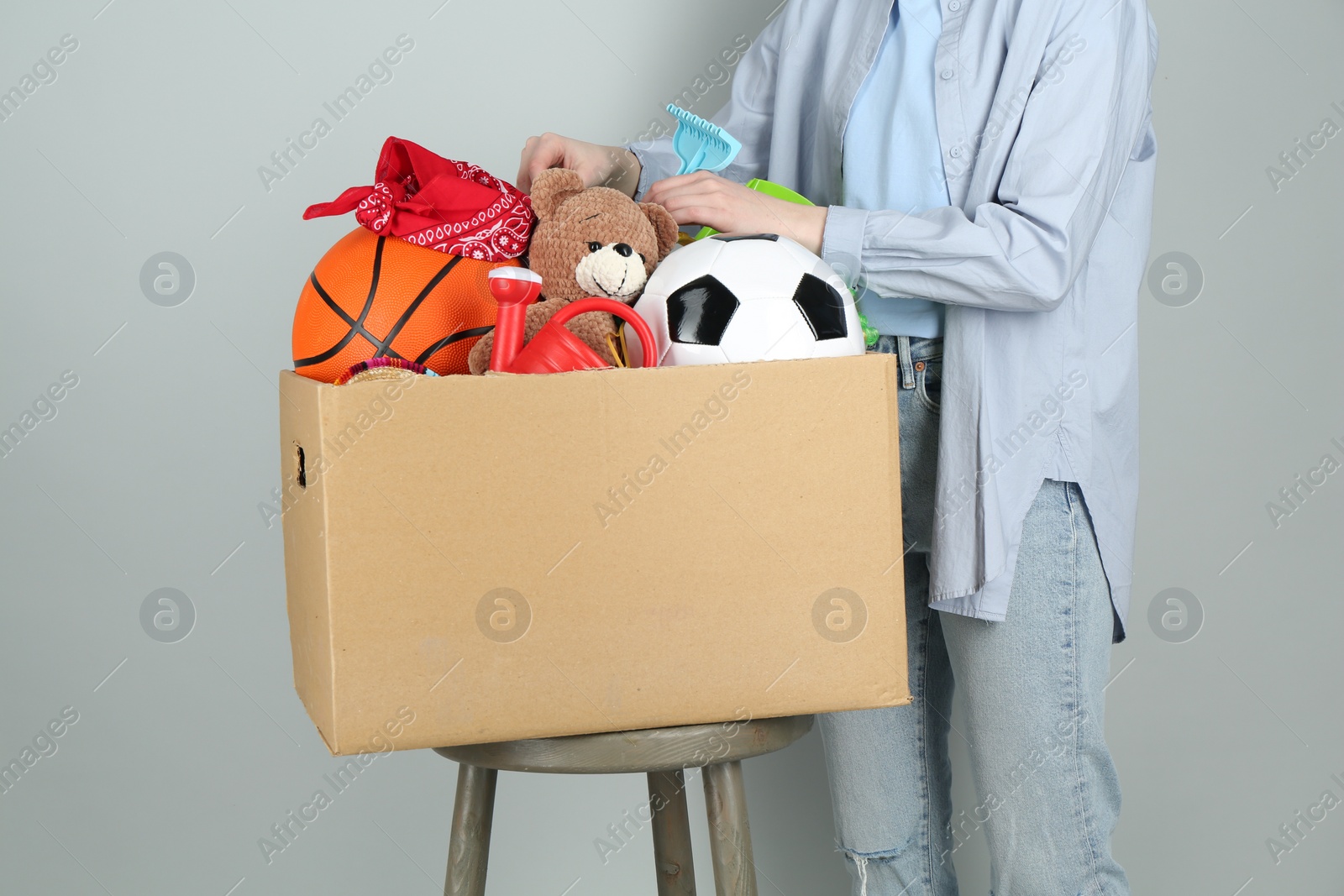 Photo of Woman with box of unwanted stuff on grey background, closeup