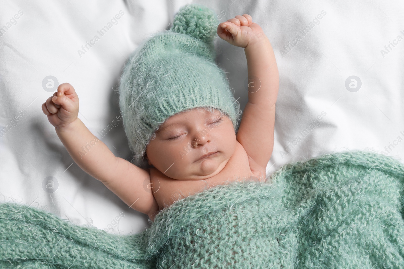 Photo of Cute little baby sleeping under knitted plaid in bed, top view