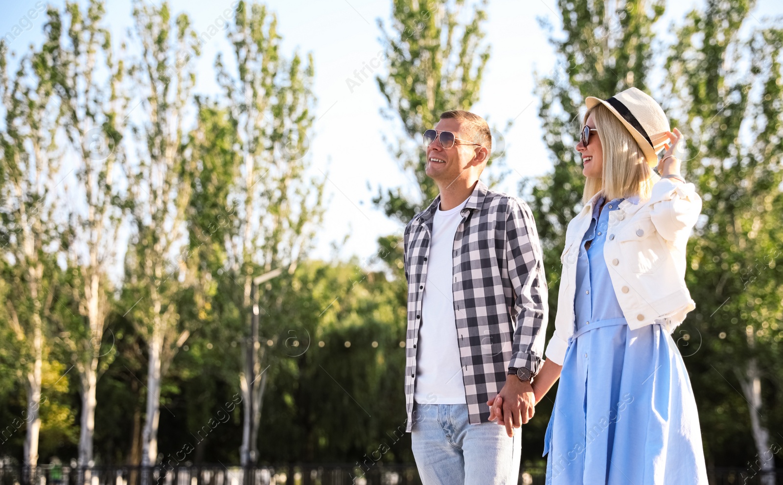 Photo of Happy couple walking along city street on summer day