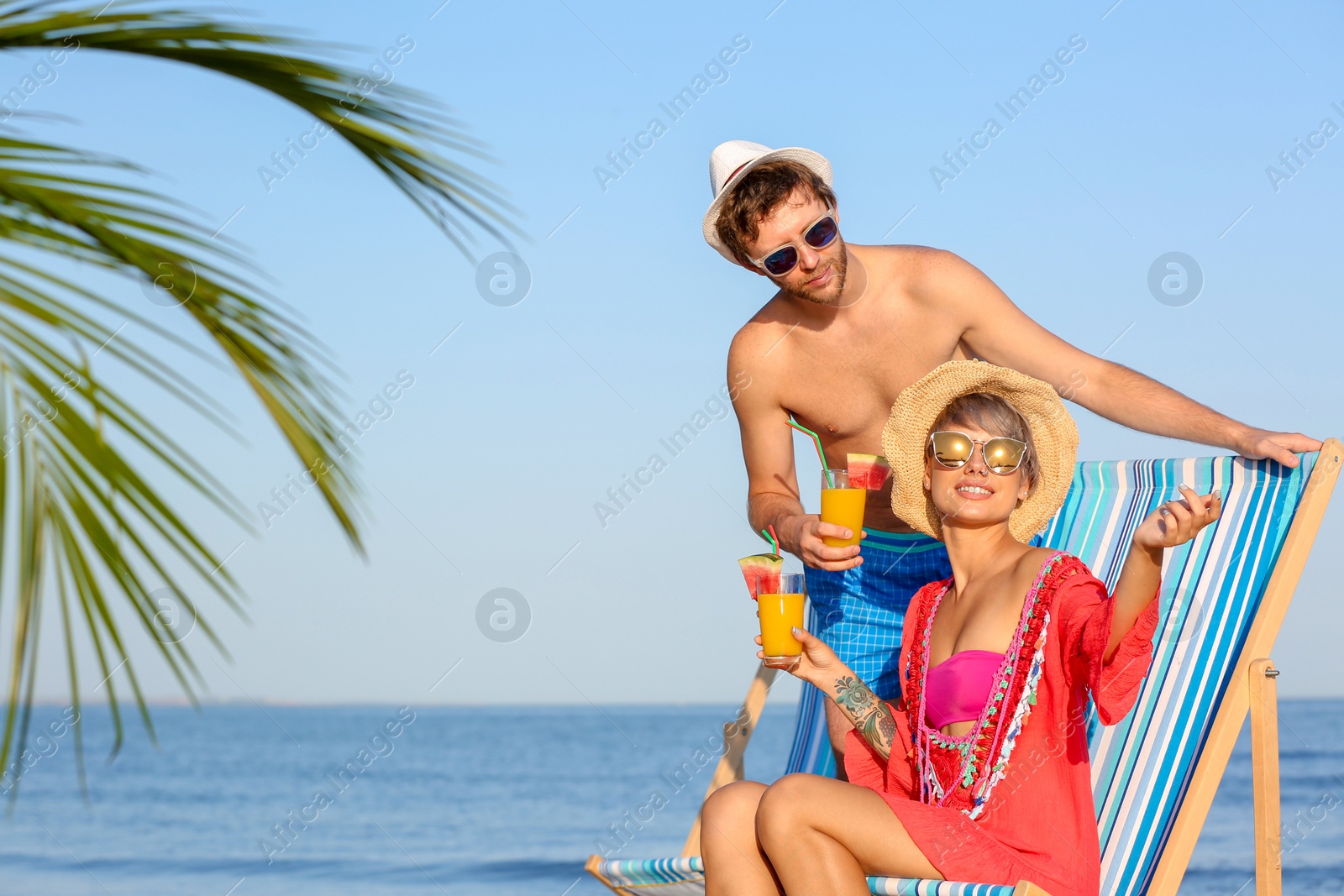 Photo of Young couple with exotic cocktails on beach. Space for text