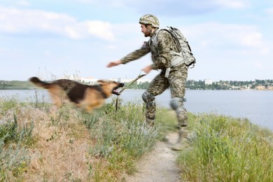 Man in military uniform with German shepherd dog outdoors