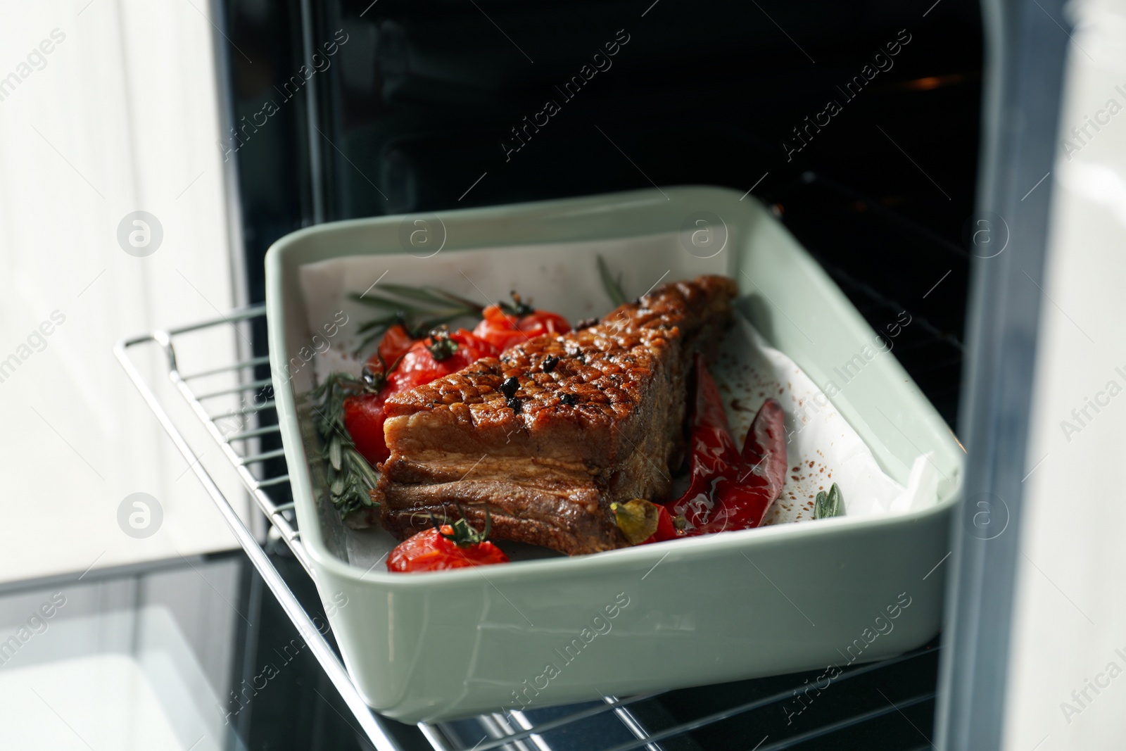 Photo of Delicious roasted ribs with tomatoes in oven