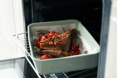 Delicious roasted ribs with tomatoes in oven