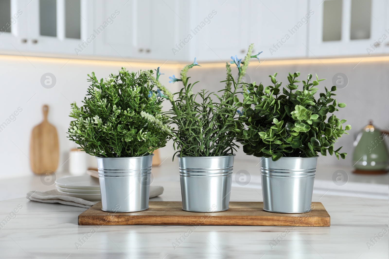 Photo of Different artificial potted herbs on white marble table in kitchen