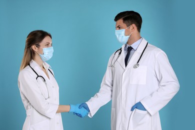 Doctors shaking hands on light blue background