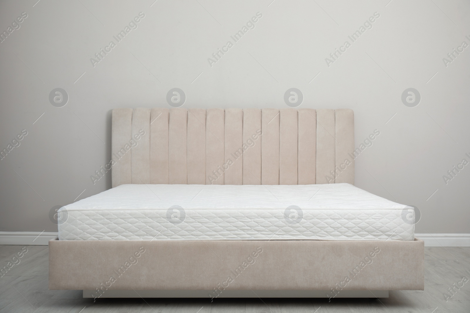 Photo of Comfortable bed with modern orthopedic mattress near grey wall indoors