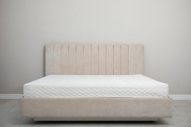 Photo of Comfortable bed with modern orthopedic mattress near grey wall indoors