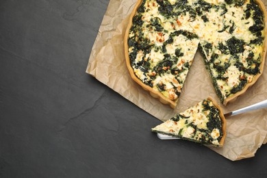 Photo of Delicious homemade spinach quiche on black table, flat lay. Space for text