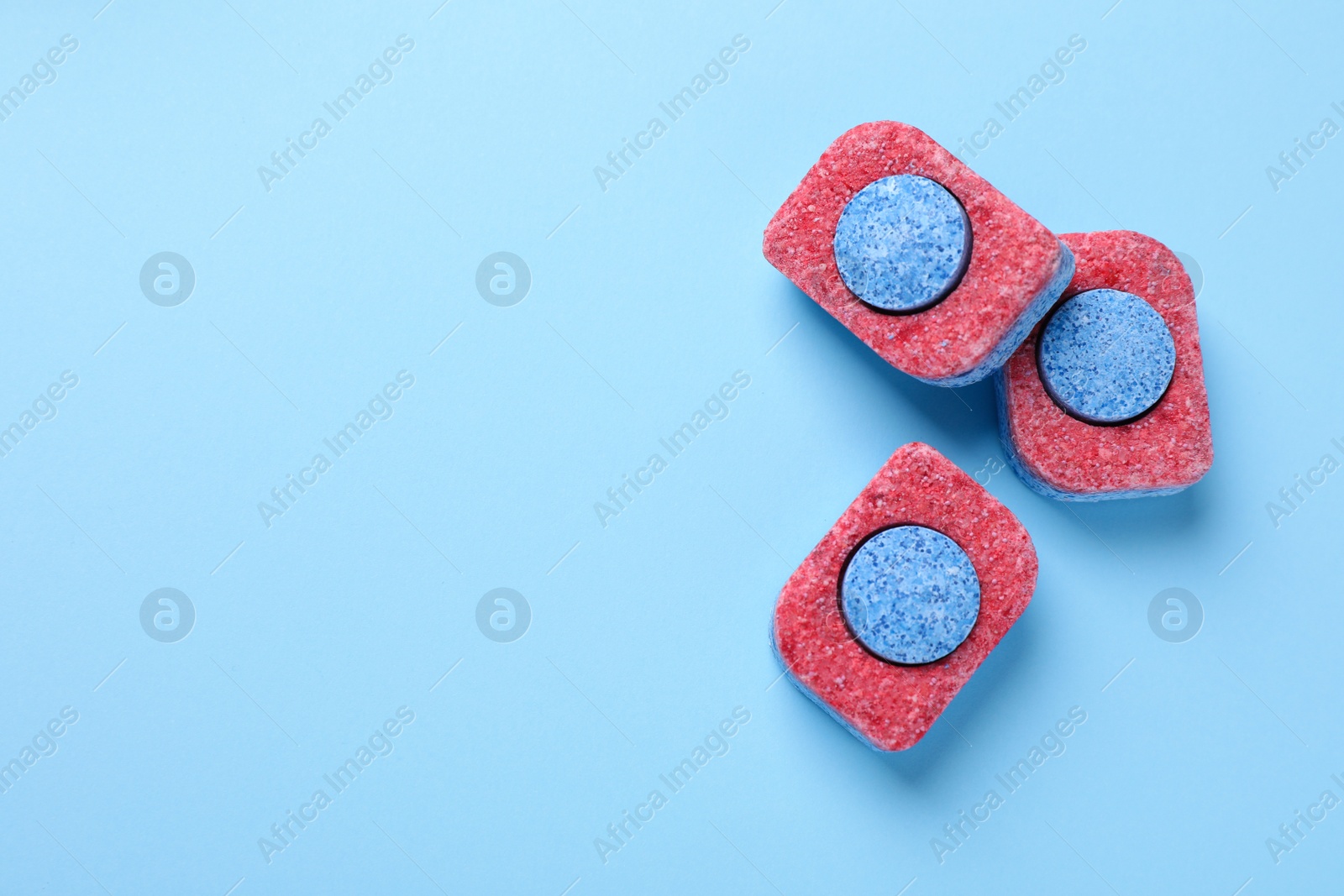 Photo of Dishwasher detergent tablets on light blue background, flat lay. Space for text