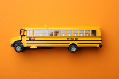 Photo of Yellow school bus on orange background, top view. Transport for students