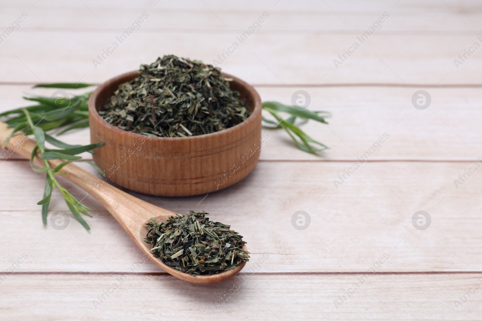 Photo of Dry and fresh tarragon on wooden table, space for text