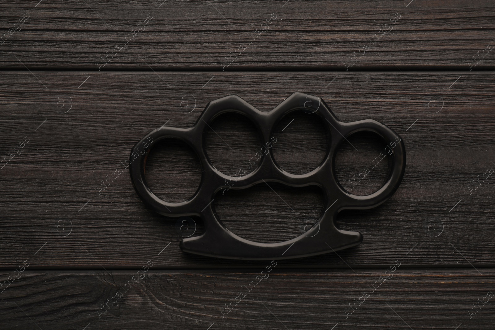 Photo of Brass knuckles on black wooden background, top view