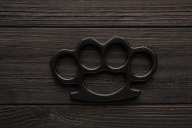 Photo of Brass knuckles on black wooden background, top view