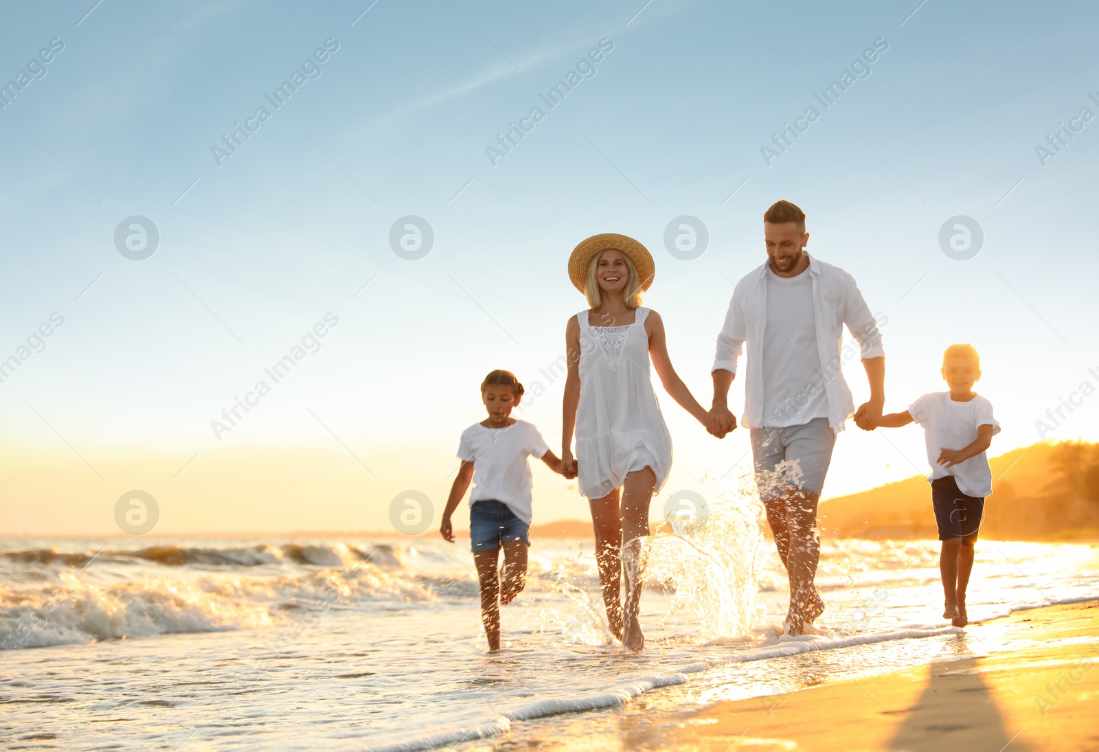 Photo of Happy family on sandy beach near sea at sunset