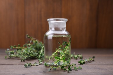 Photo of Natural thyme essential oil on wooden table