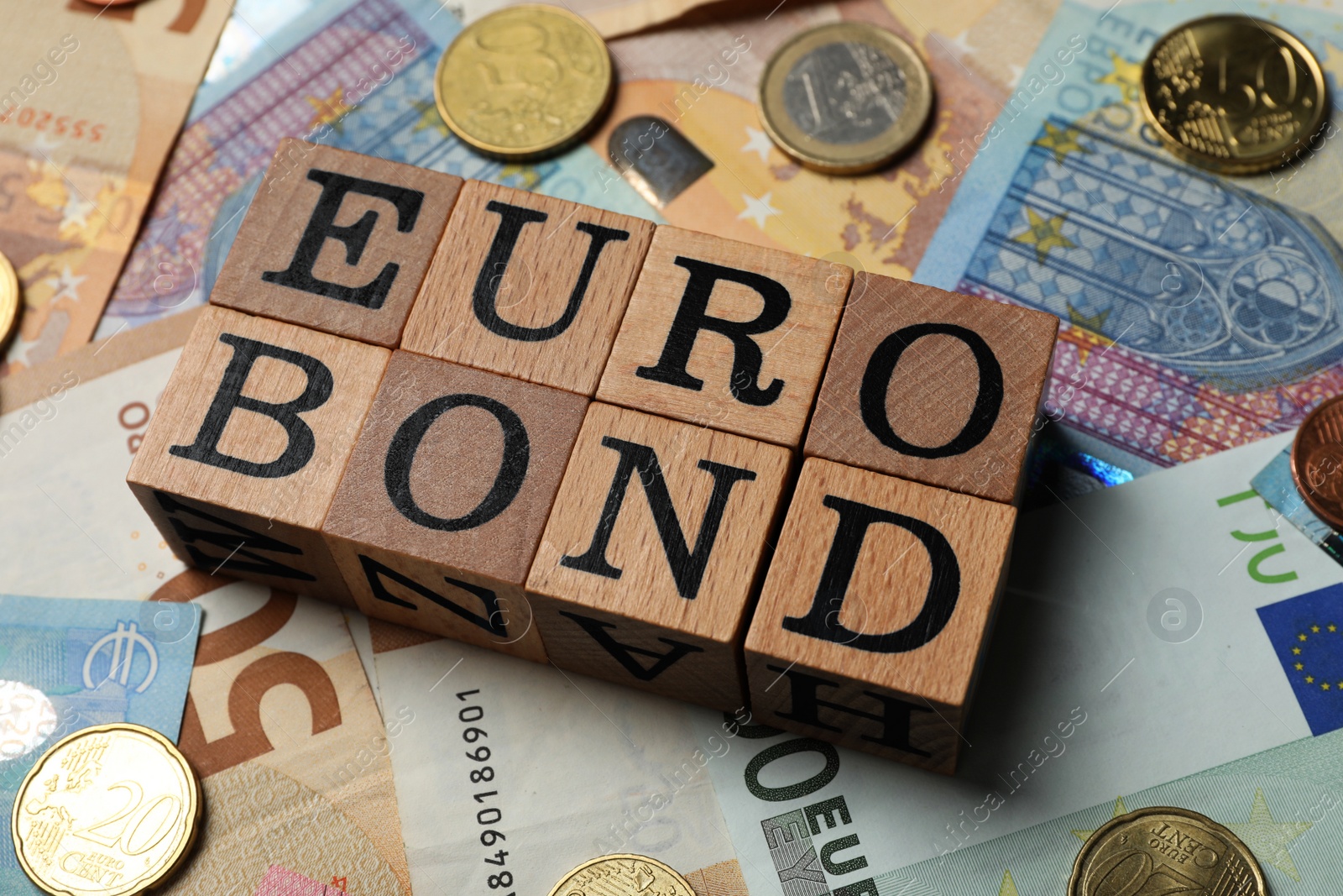 Photo of Wooden cubes with word Eurobond and coins on euro banknotes
