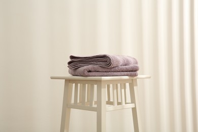 Violet towels on stool against white wall