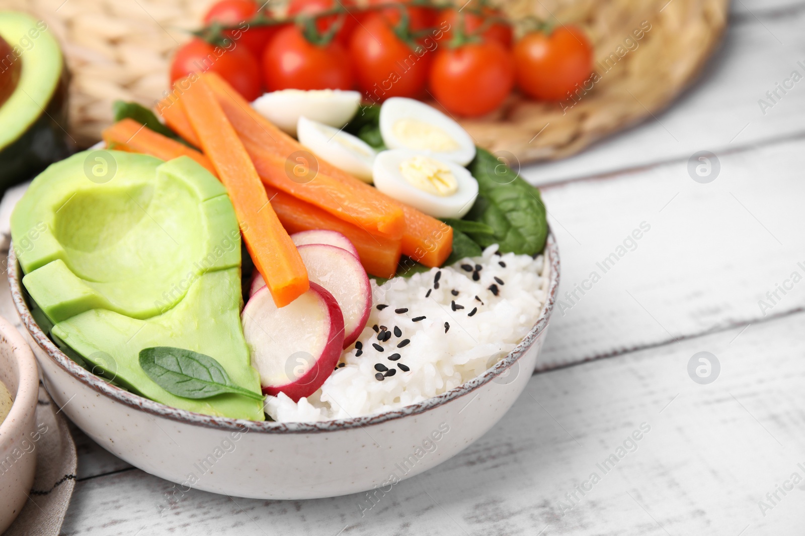 Photo of Delicious poke bowl with basil, eggs, avocado and vegetables on white wooden table, closeup