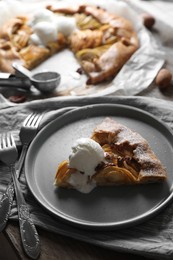 Photo of Delicious apple galette served with ice cream on wooden table