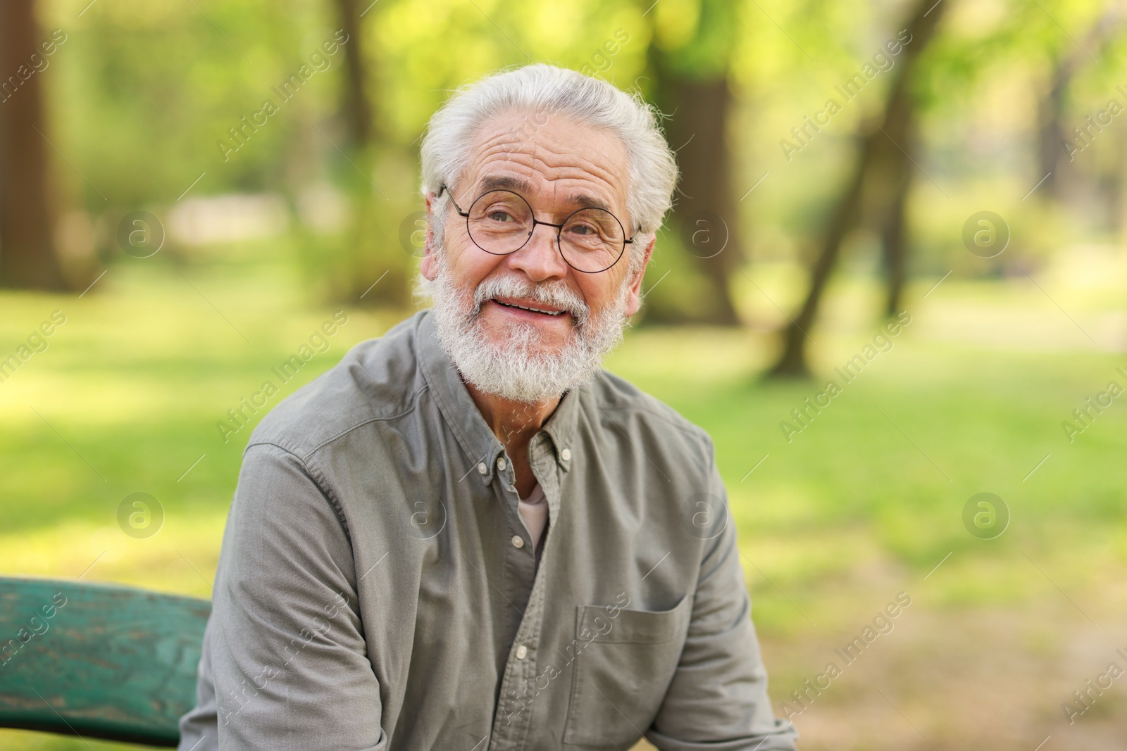 Photo of Portrait of happy grandpa with glasses on bench in park