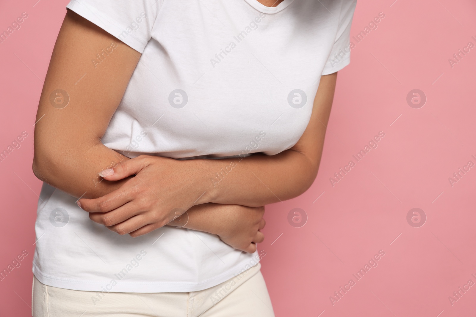 Photo of Young woman suffering from menstrual pain on pink background, closeup. Space for text