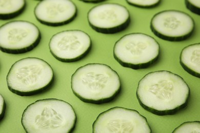 Photo of Fresh slices of cucumbers on green background, closeup